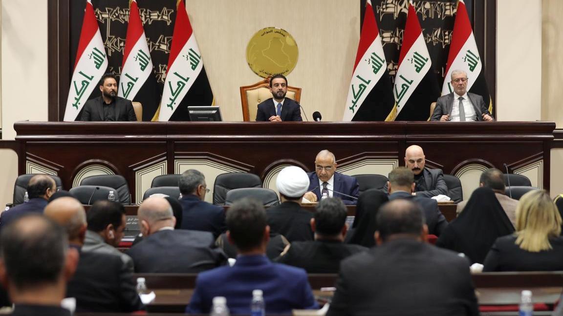 Iraqi flags wave behind a group of men in parliament