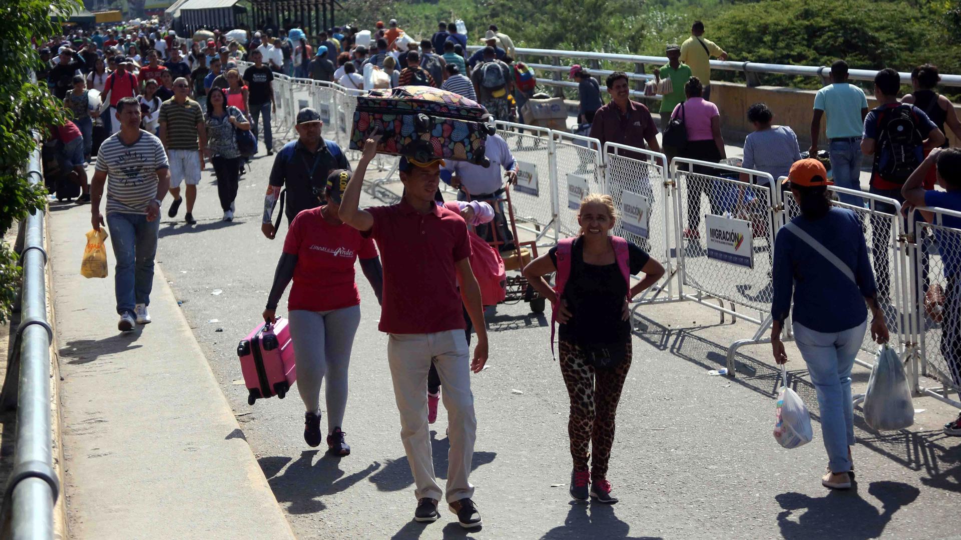 People walk across a bridge at the border with Venezuela 
