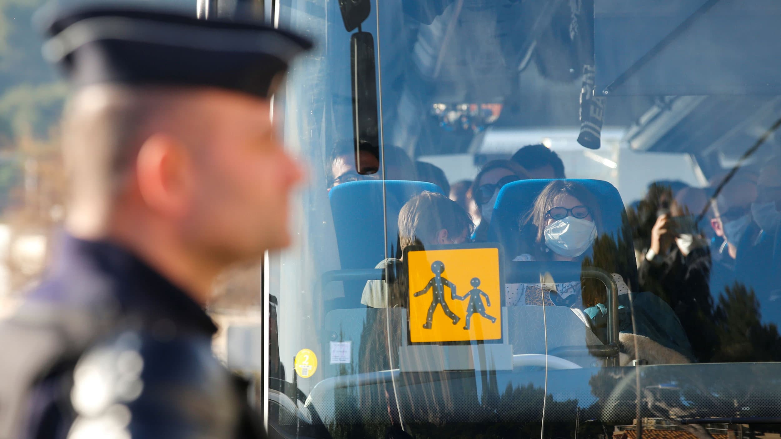 A large bus is shown with people sitting and wearing face masks.
