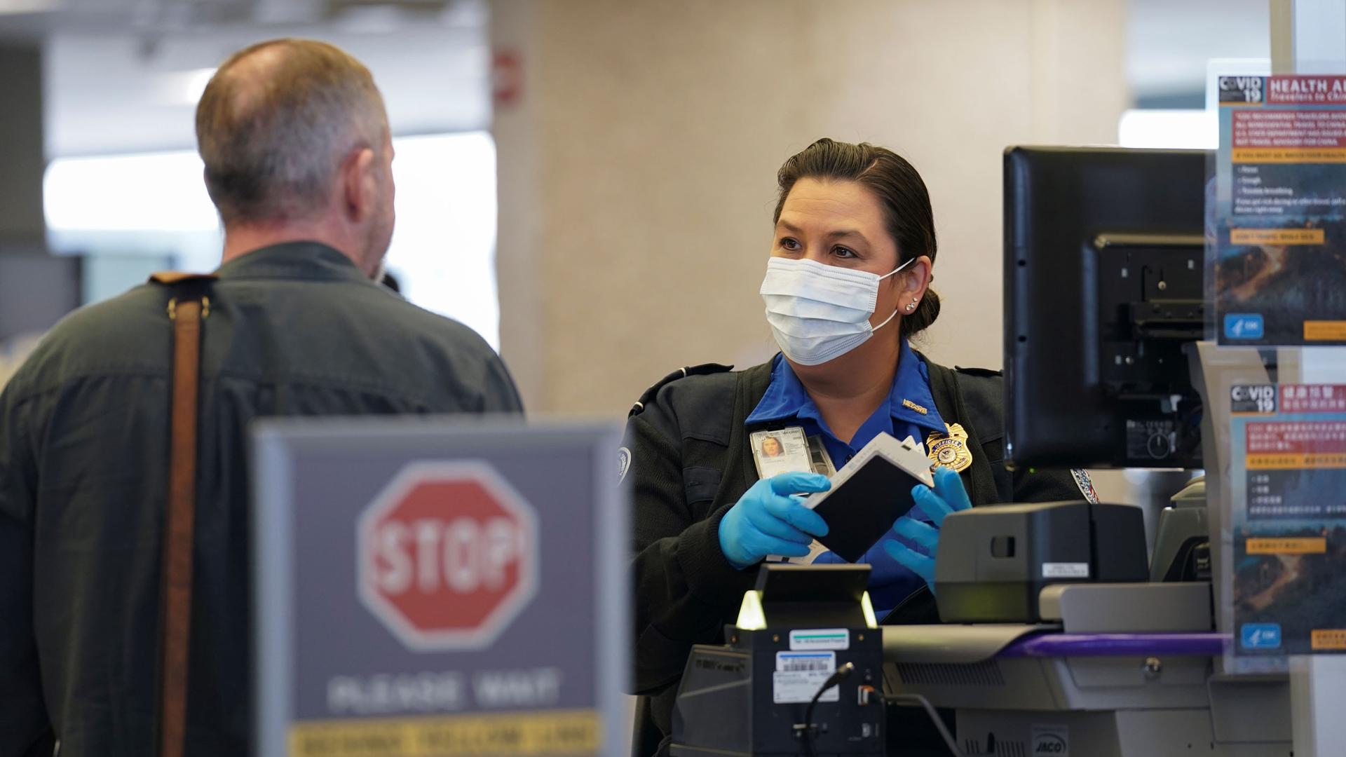 A TSA officer wearing a face mask clears a departing passenger
