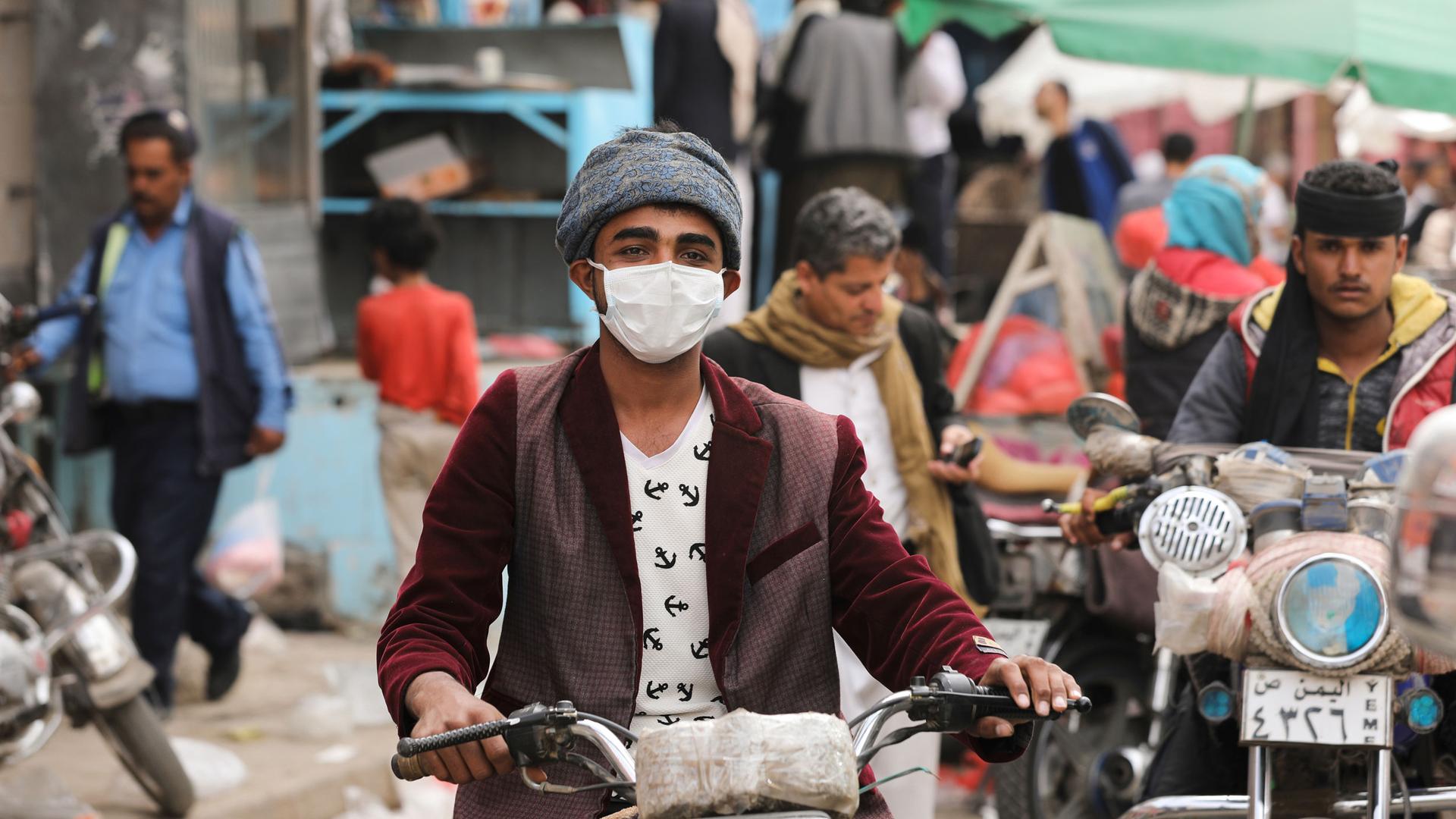 A man wears a protective face mask as he rides a motorcycle