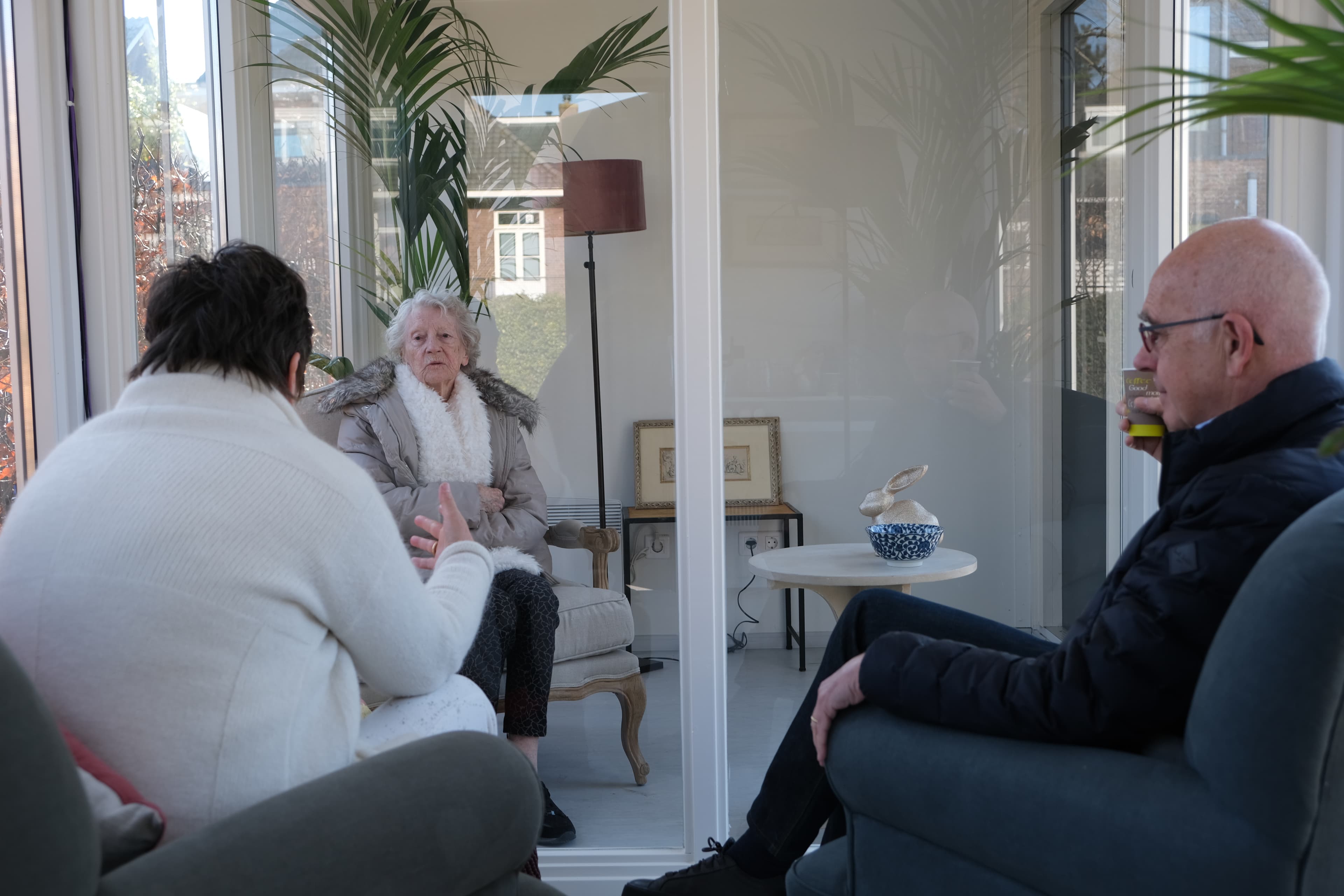 Two adults visit with an elder in a 