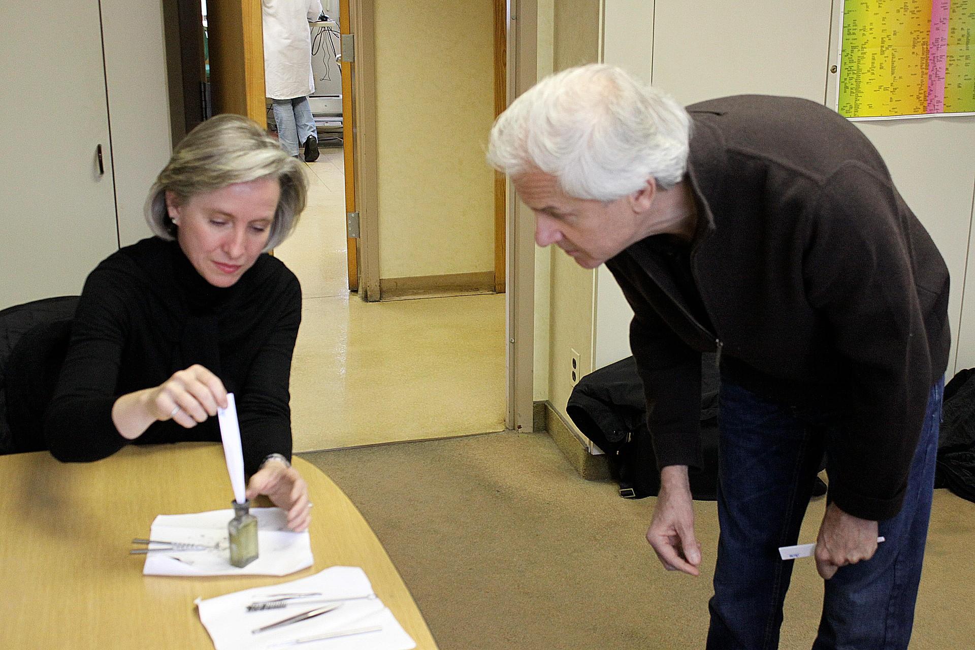 A woman and a man look at a perfume bottle.