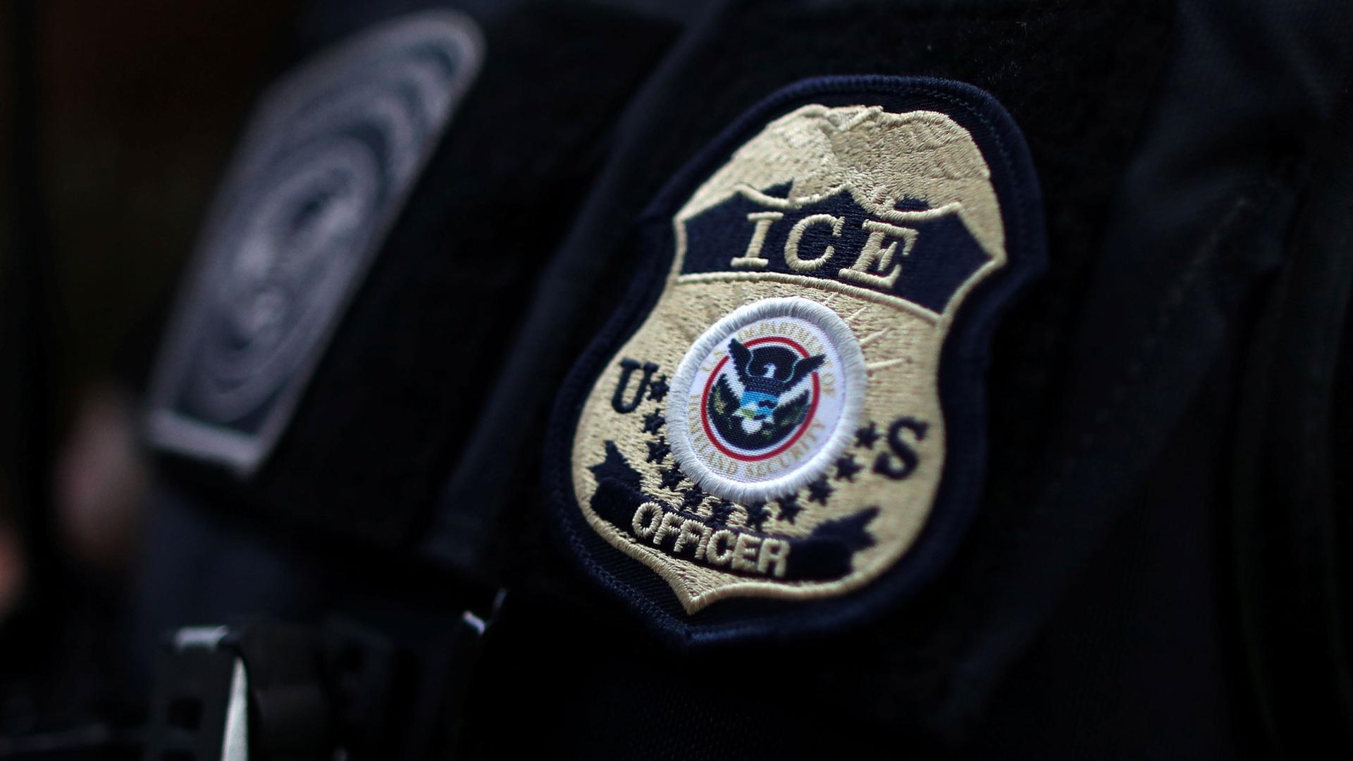 The sewn badge of an ICE officer is shown on the shoulder of an offfical.