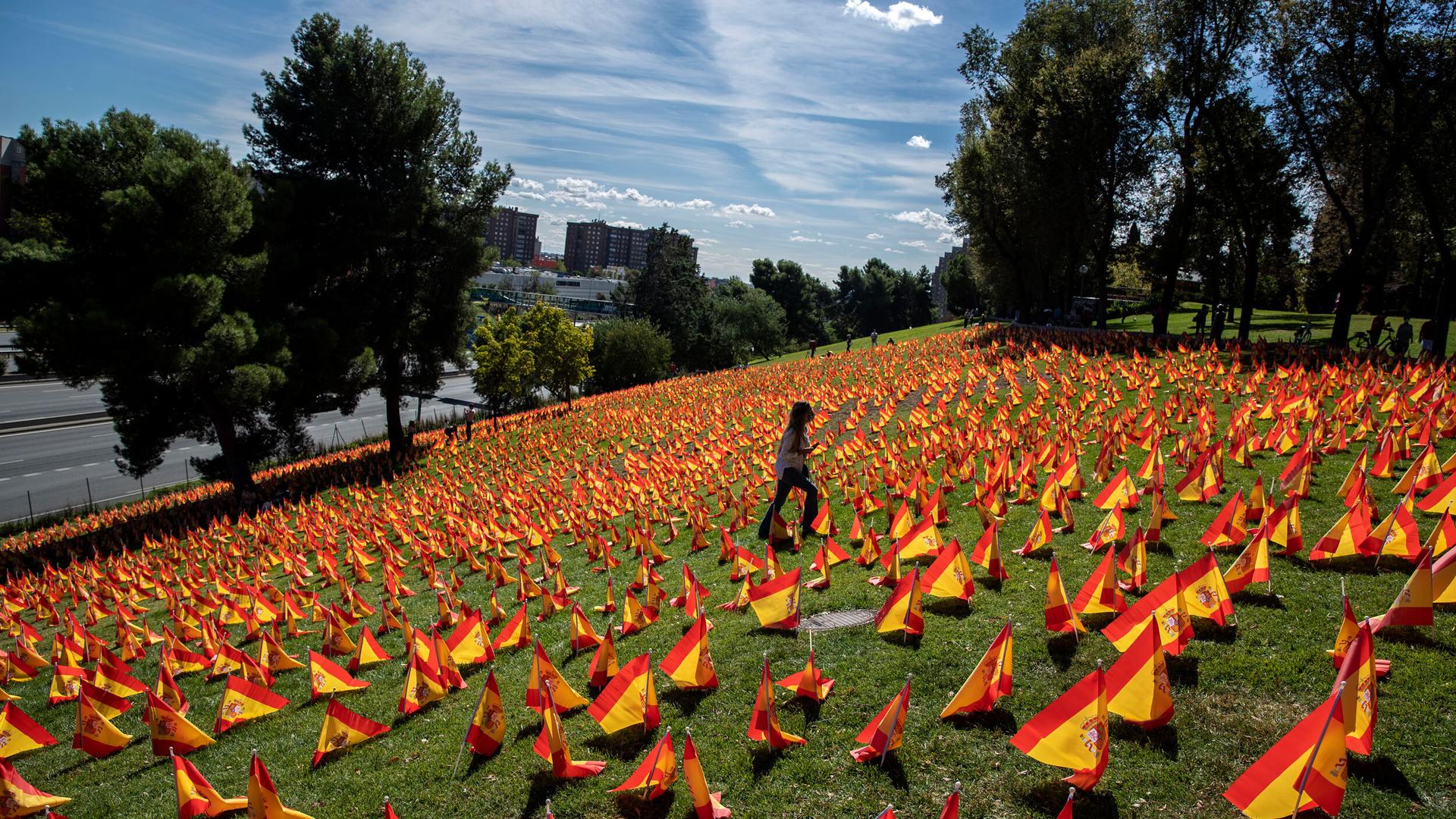 A woman walks among the Spanish flags placed in memory of coronavirus victims in Madrid, Spain, Sept. 27, 2020.