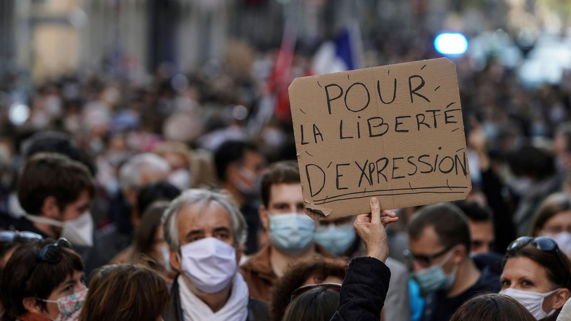 A large crowd of demonstrators are with one person holding a sign that read, "Pour La Liberte D'Espression," or "For the freedom of speech" in English.