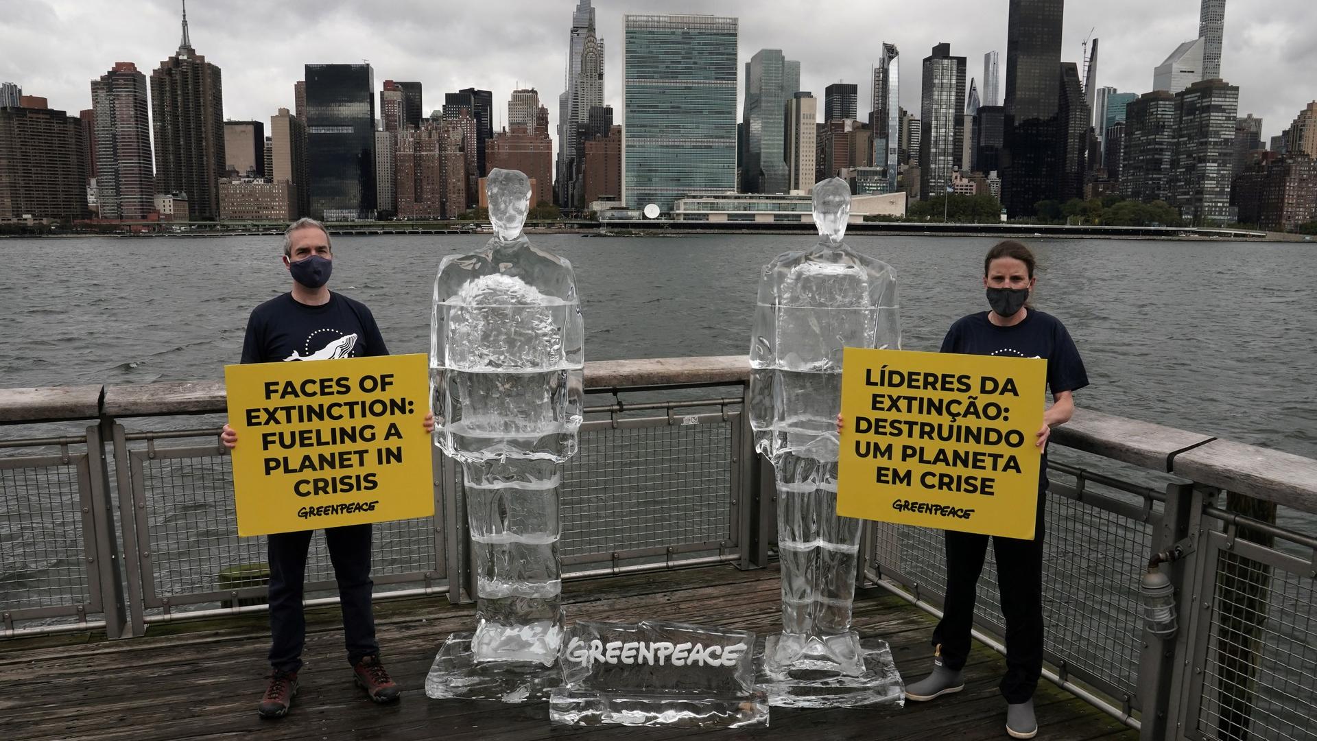 Greenpeace activists hold signs between two ice sculptures depicting US President Donald Trump and Brazil's President Jair Bolsonaro across the Hudson River from UN headquarters in the Queens borough of New York City, Sept. 30, 2020.