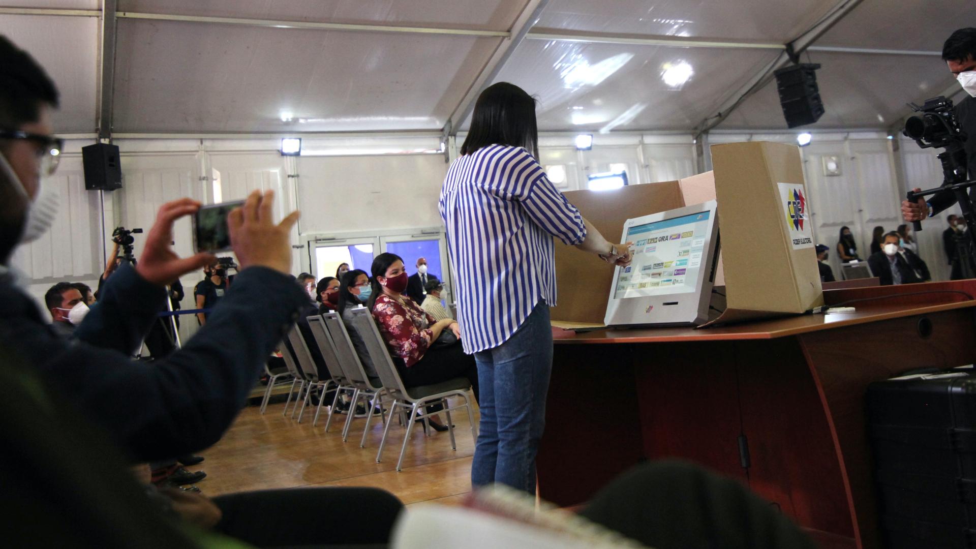 A woman simulates her vote as Venezuela's National Electoral Council presents the technology platform for parliamentary elections in Caracas, Venezuela, Oct. 9, 2020. 