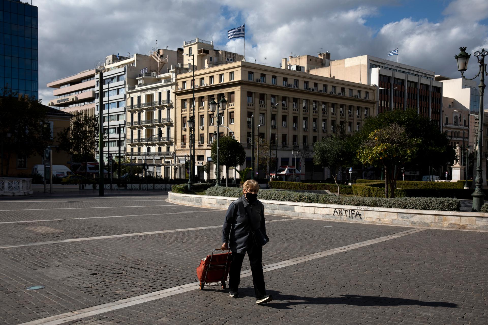 A woman, wearing a protective mask against the spread of coronavirus, walks at a central square, in Athens, Greece, Nov. 21, 2020. 