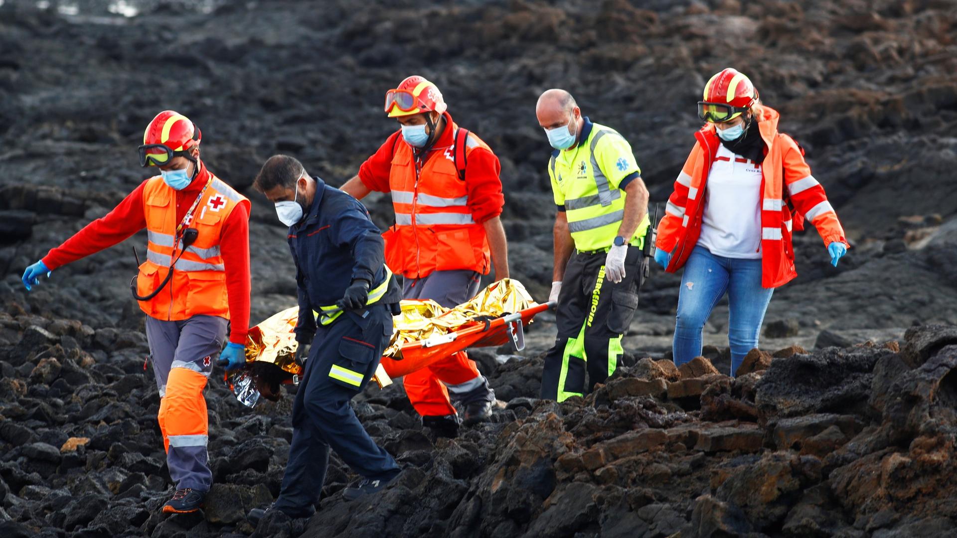 Rescue workers carry the body of a dead migrant after a boat with 35 migrants from the Maghreb region capsized at the beach of Orzola, in the Canary Island of Lanzarote, Spain, Nov. 25, 2020.