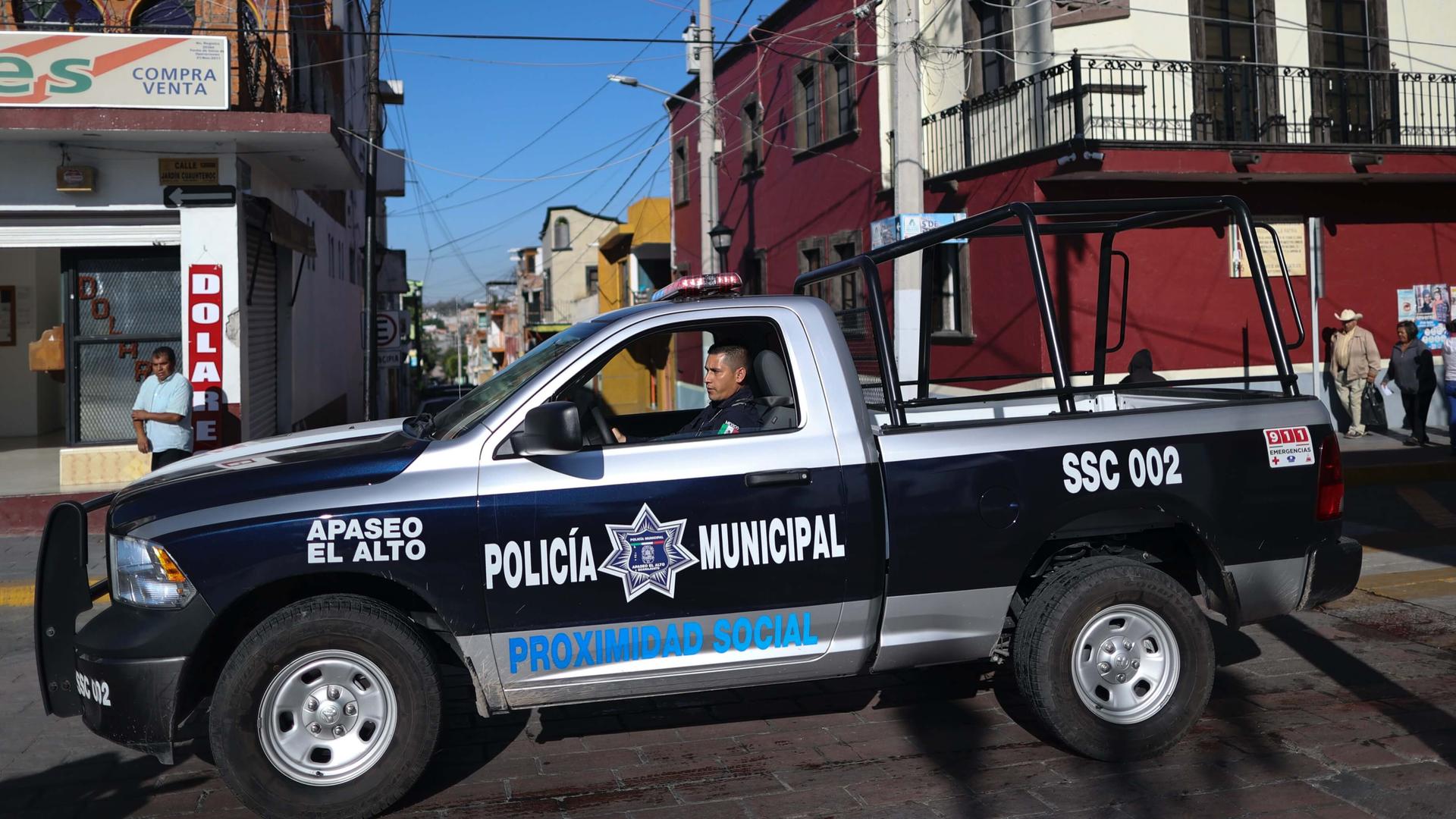 A police officer drives a large blue and white police vehicle through town