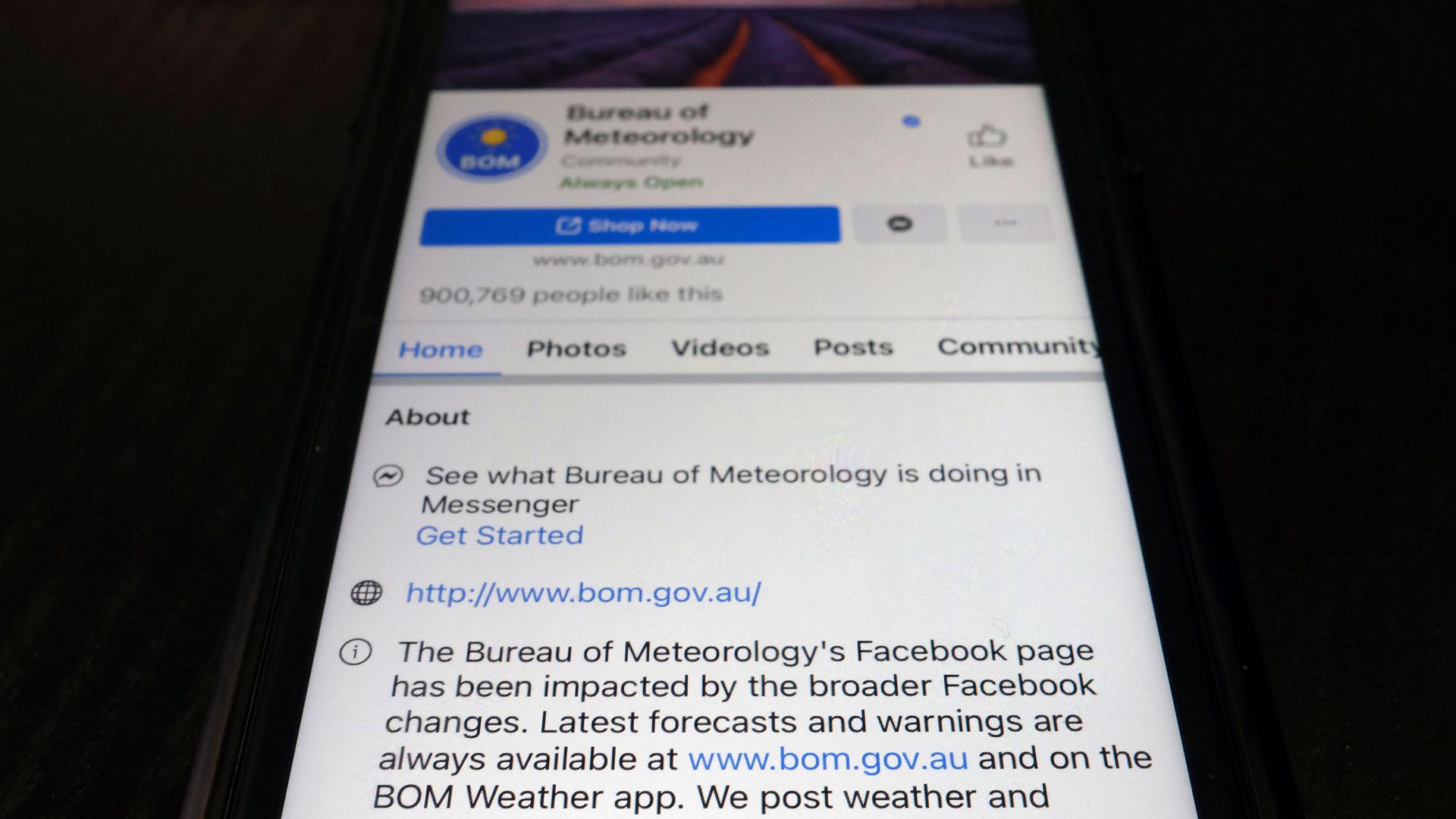 A close up photograph of a mobile phone showing the Bureau of Meteorology's page on the Facebook app.