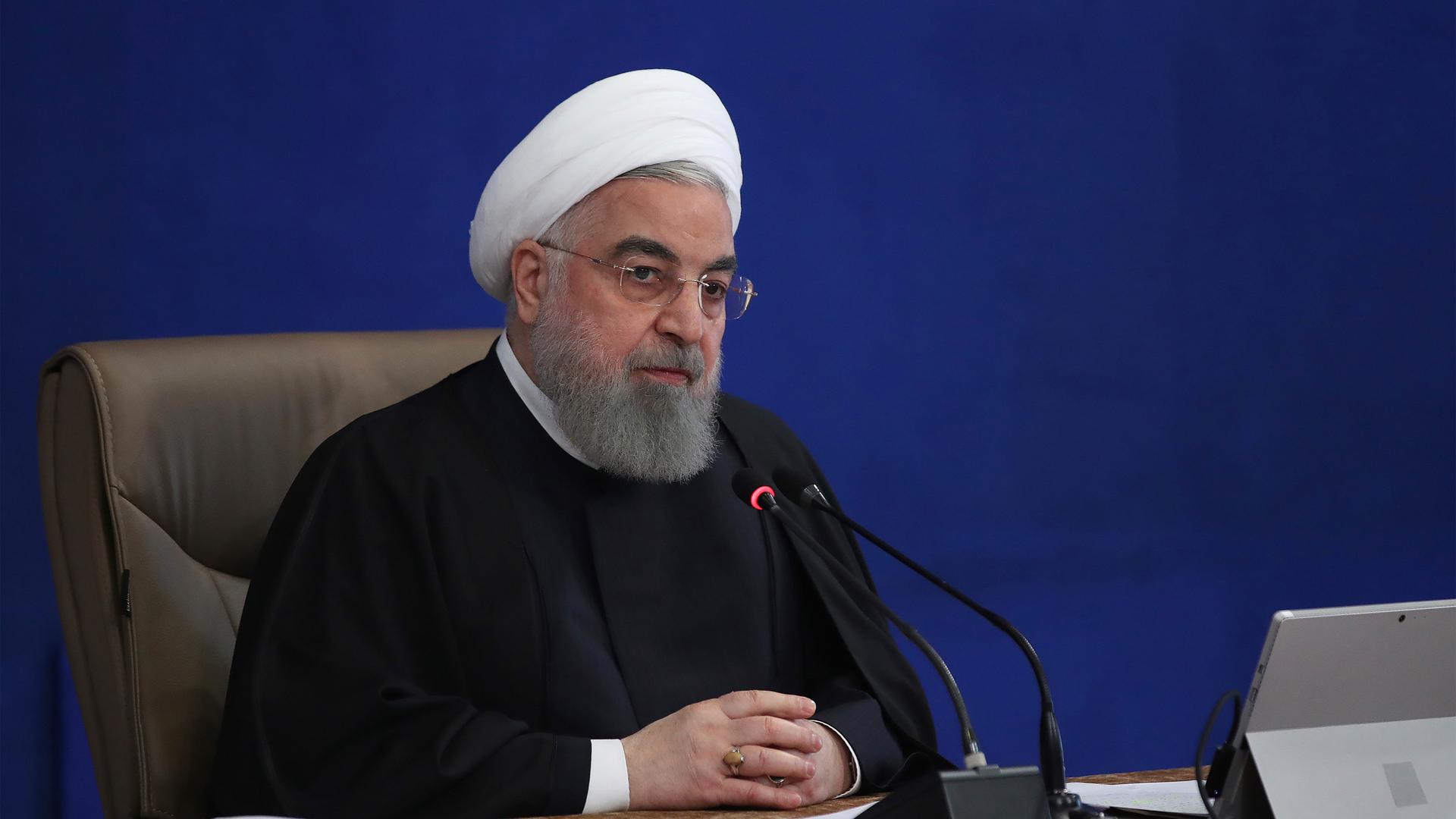 President Hassan Rouhani is shown wearing a dark robe and a traditional white turban while sitting.