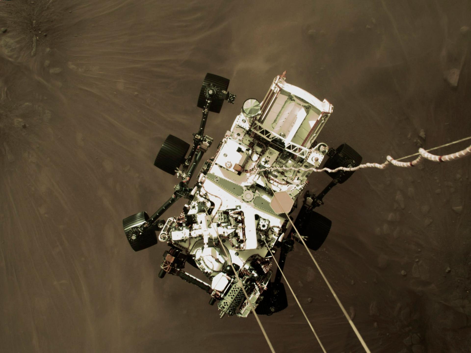 This Feb. 18, 2021, photo provided by NASA shows the Perseverance rover lowered toward the surface of Mars during its powered descent.