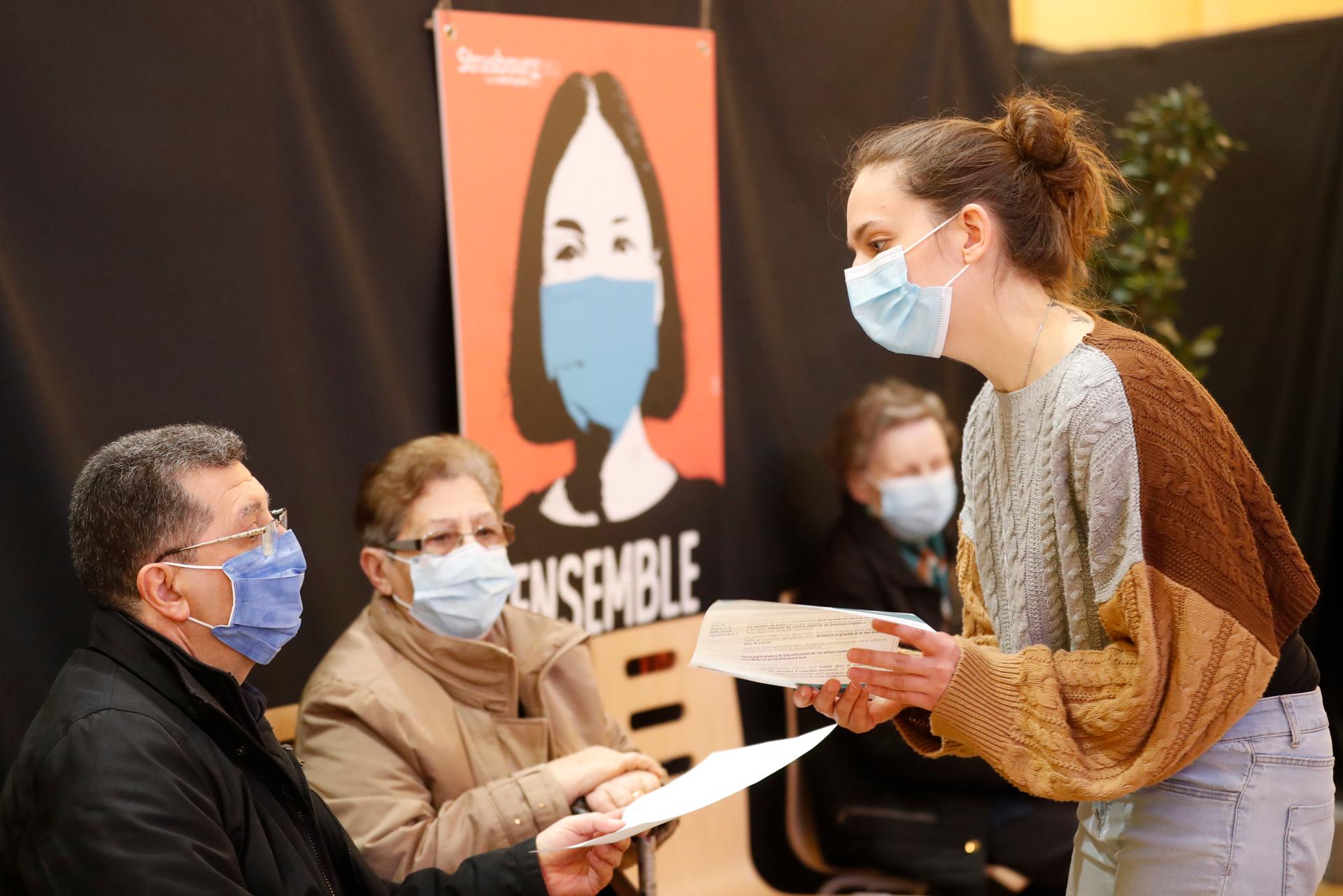 An administrative worker explains to people how to fill up the national vaccination certificate in a vaccination center in Strasbourg, France, March 18, 2021. France is set to announce new coronavirus restrictions on Thursday, including a potential lockdo
