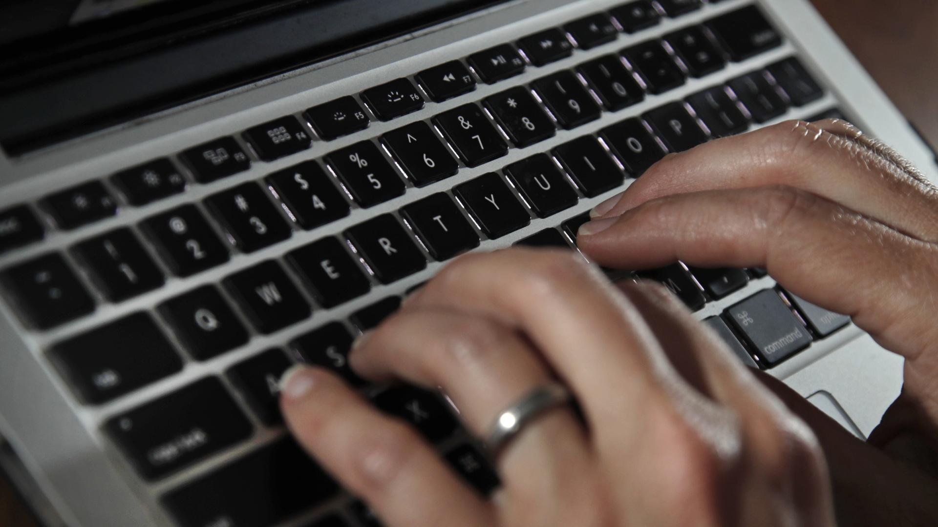 Fingers type on a laptop keyboard