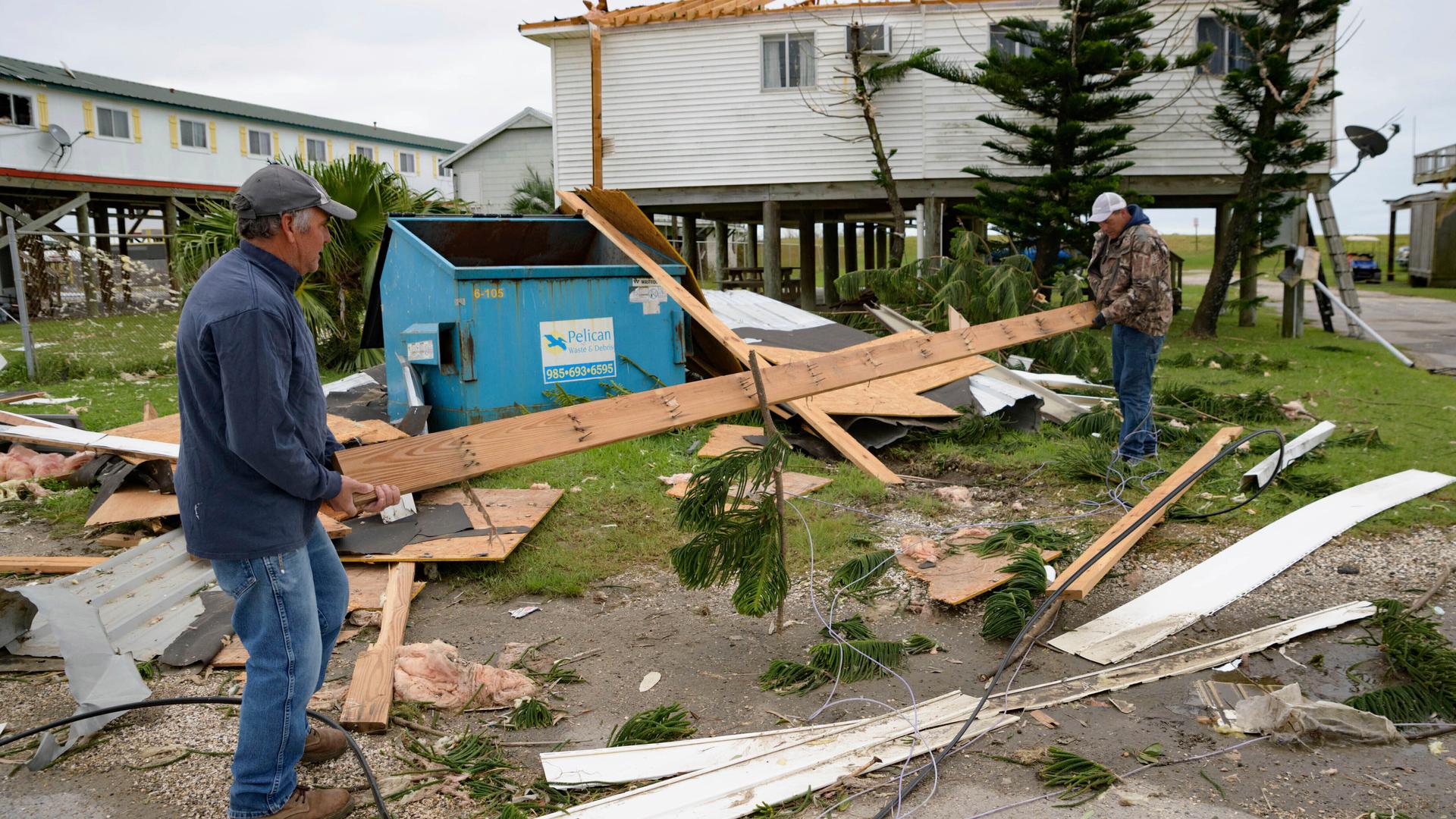 In this Oct. 30, 2020, file photo, Mark Andollina, left, and Shane Holder, remove part of a roof damaged by Hurricane Zeta