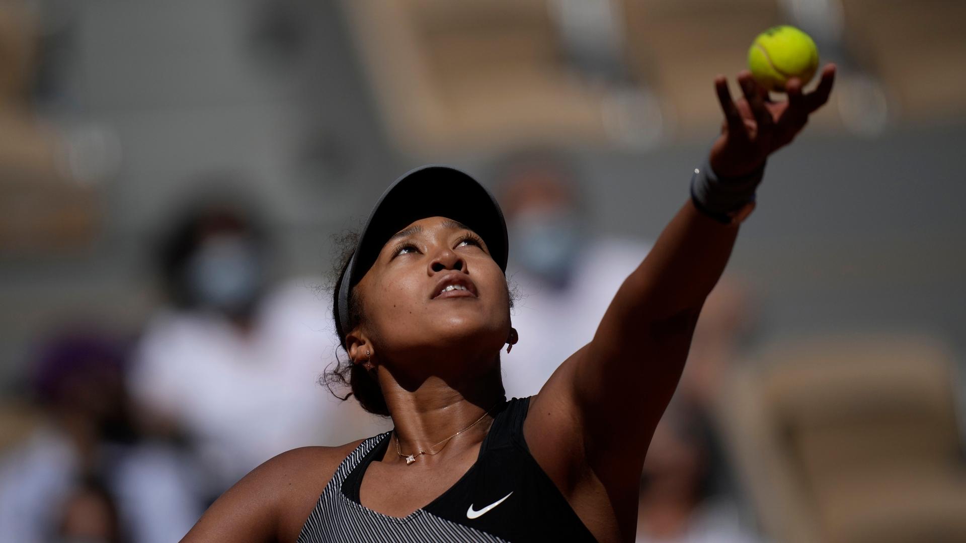 A tennis player lifts her ball and racket into the air.