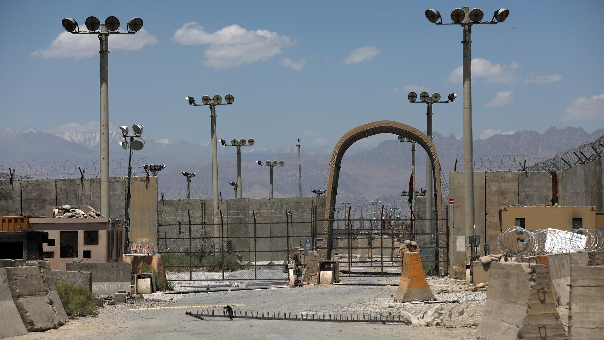 Several tall lamp posts are shown with an arched stone gate with fencing and barbed wire.