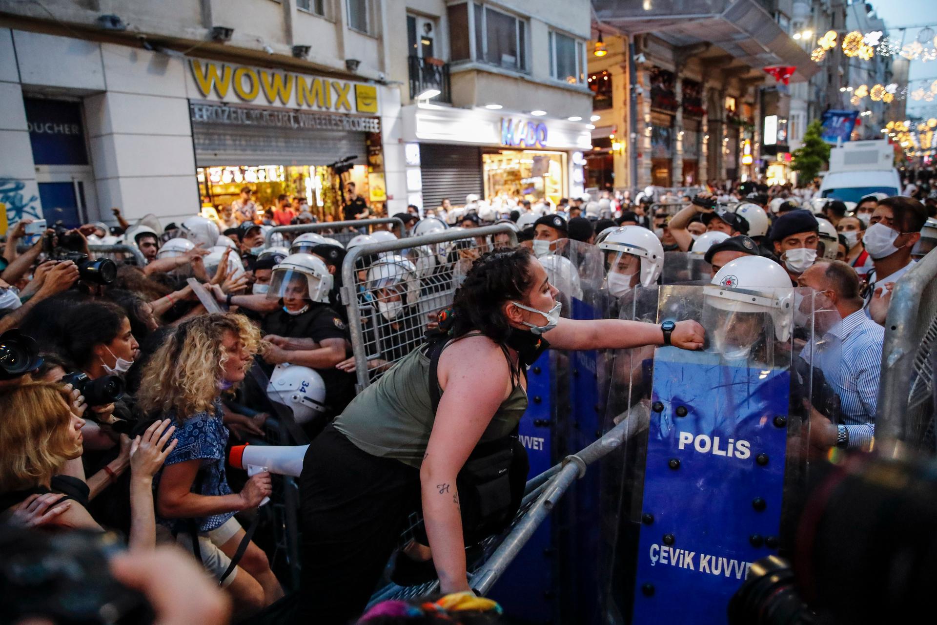 Protesters, left, clash with police officers preventing them from marching against the government's decision to withdraw from Istanbul Convention, in Istanbul, Thursday, July 1, 2021.