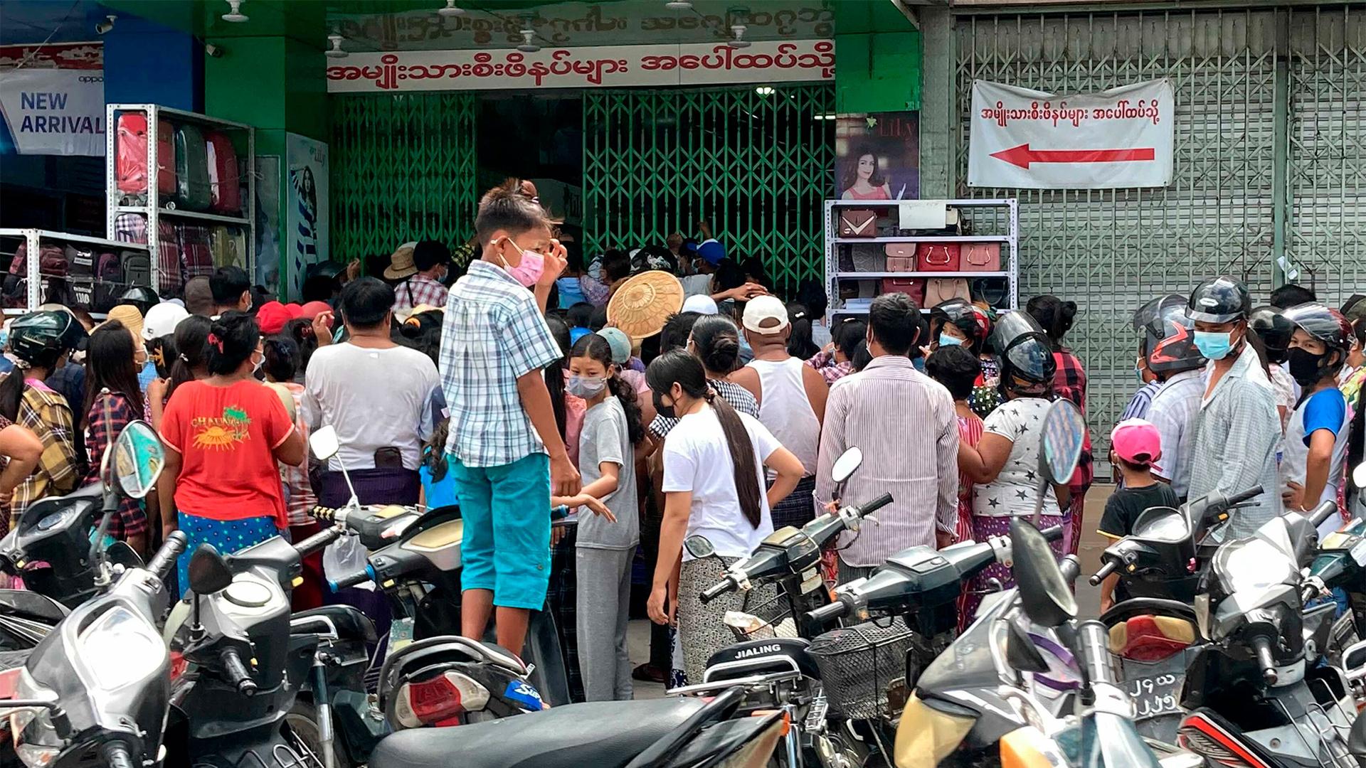 People wait outside a shop where face masks and vitamins are being given away in Mandalay, Myanmar