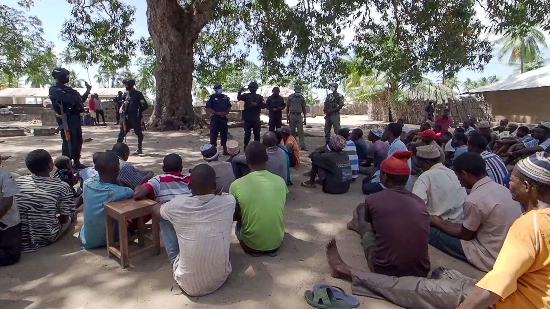 In this image made from video, Rwandan and Mozambican police speak to returnees in Palma, Cabo Delgado province, Mozambique