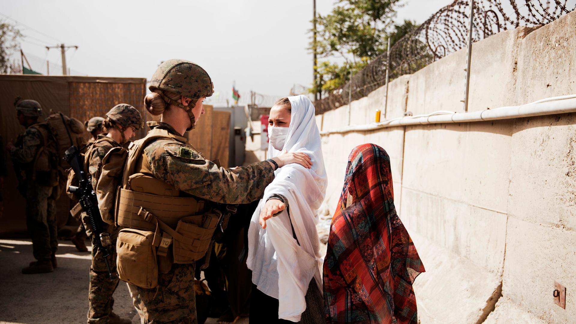 In this photo provided by the US Marine Corps, two civilians during processing through an Evacuee Control Checkpoint during an evacuation at Hamid Karzai International Airport, in Kabul, Afghanistan, Wednesday, Aug. 18, 2021. 