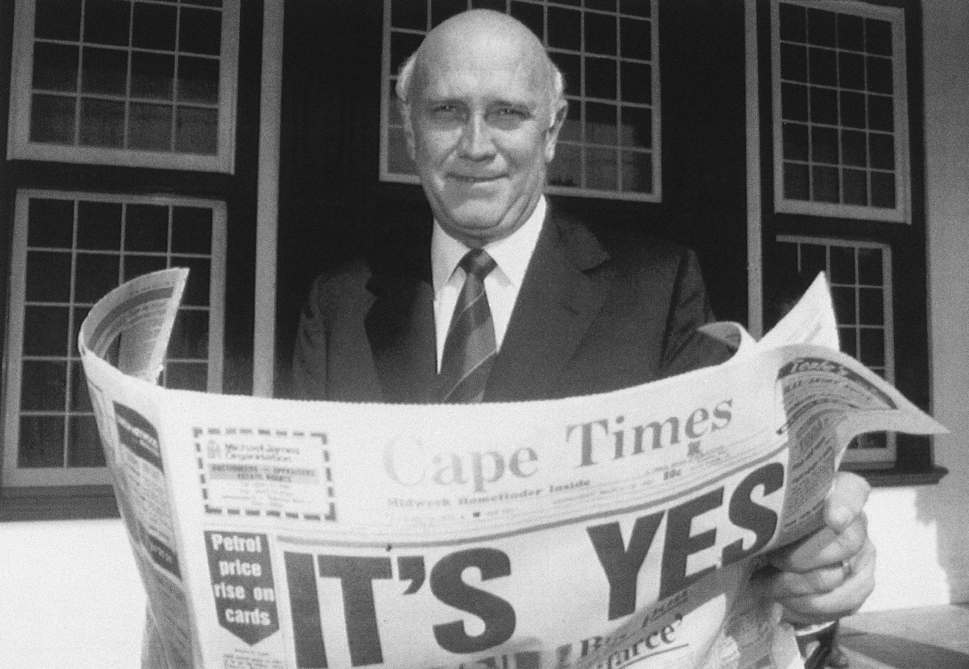 South African President FW de Klerk poses outside his office in Cape Town, South Africa March 18, 1992, while displaying a copy of a local newspaper with banner headlines declaring a 