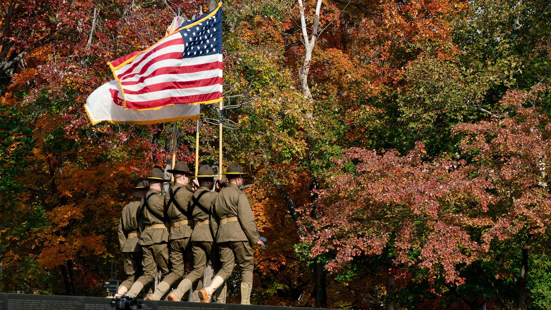 Color guard retires the colors during a Veterans Day commemoration ceremony at the Vietnam Veterans Memorial in Washington amid brightly colored trees