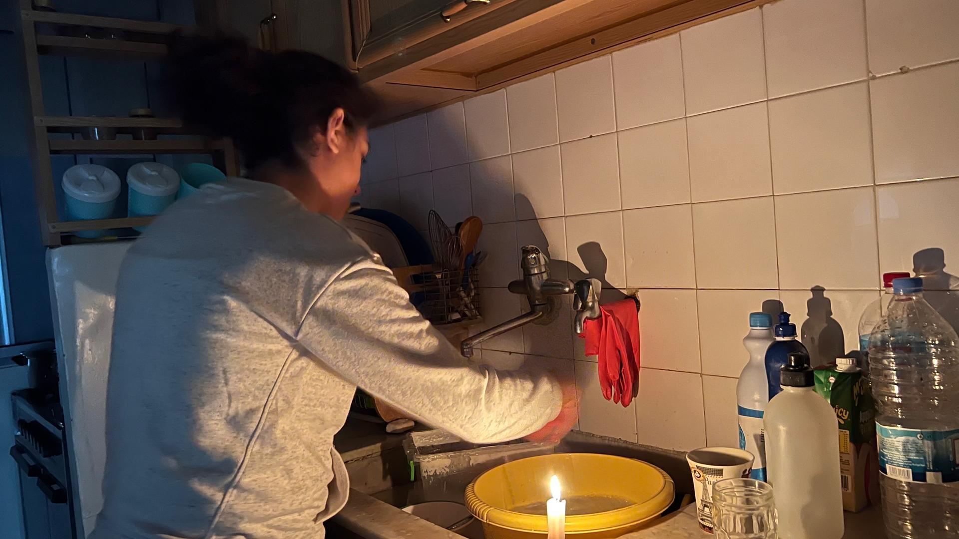 Diala Attieh Younes, 39, washes dishes under candlelight in her kitchen in Beirut. She said her generator-supplied electricity bill has increased six folds since last year.