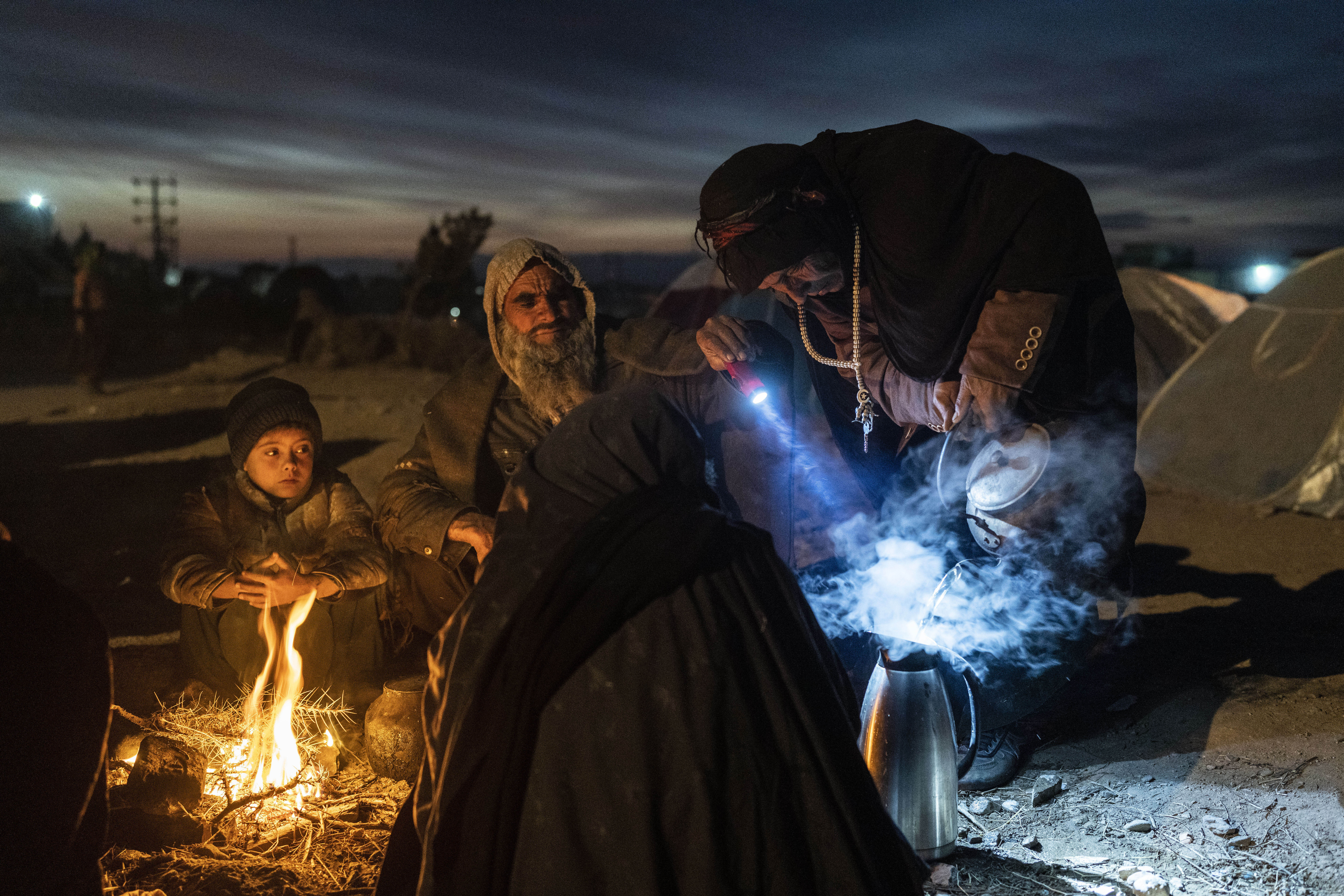 A family prepares tea outside the Directorate of Disaster office where they are camped, in Herat, Afghanistan, on Nov. 29, 2021. The United Nations is predicting that a record 274 million people — who together would amount to the world’s fourth most-popul