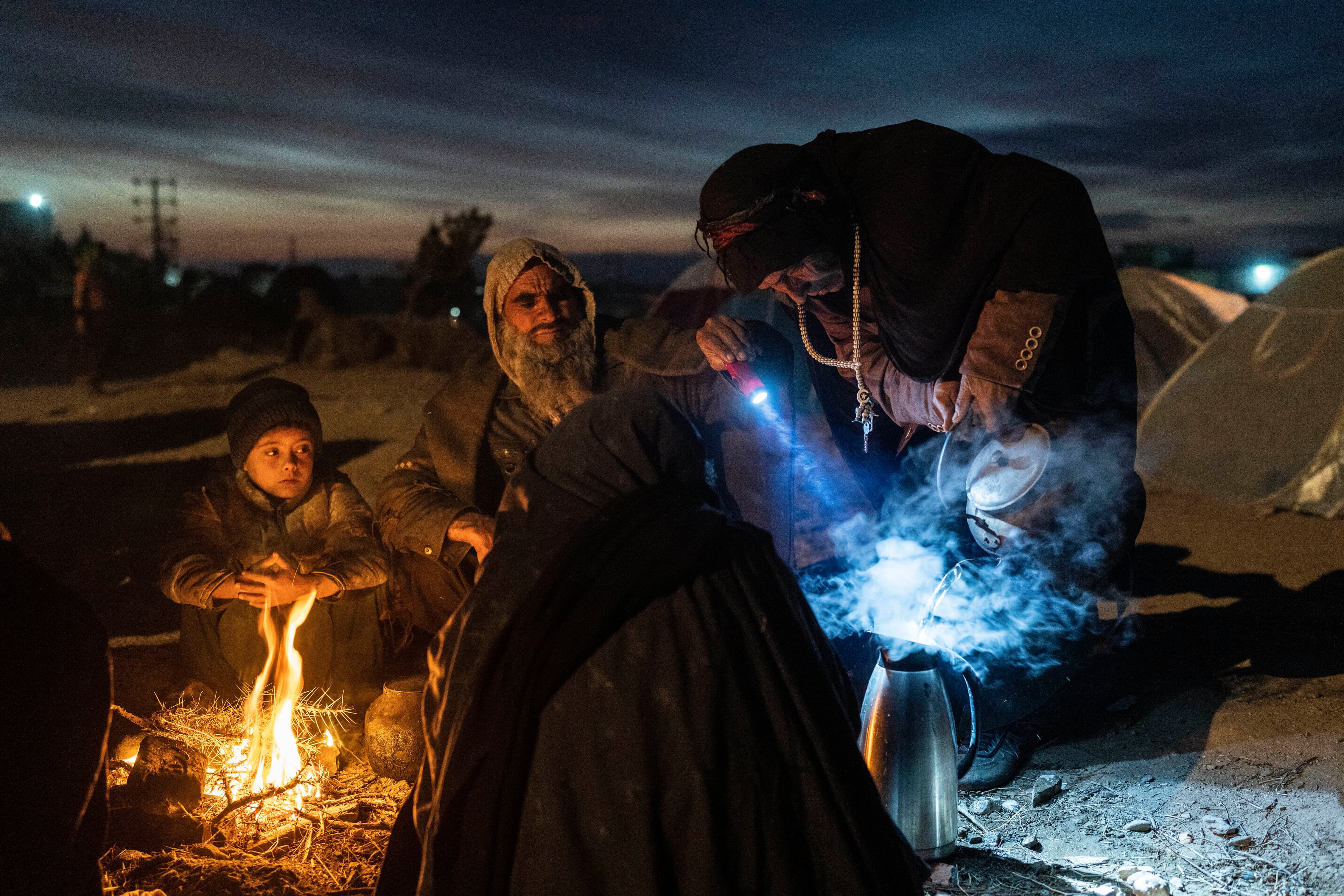 A family prepares tea outside the Directorate of Disaster office where they are camped, in Herat, Afghanistan, on Nov. 29, 2021. The United Nations is predicting that a record 274 million people — who together would amount to the world’s fourth most-popul