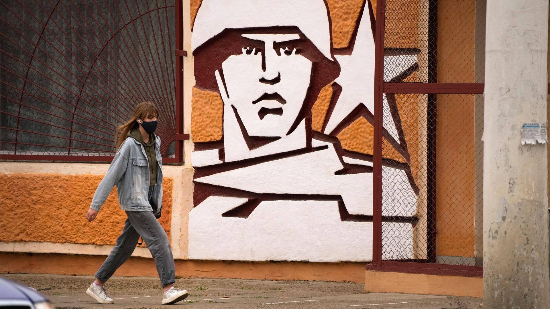 A woman walks past the Operational Group of Russian Forces headquarters in Tiraspol, the capital of the breakaway region of Transnistria, a disputed territory unrecognized by the international community, in Moldova, Nov. 1, 2021.