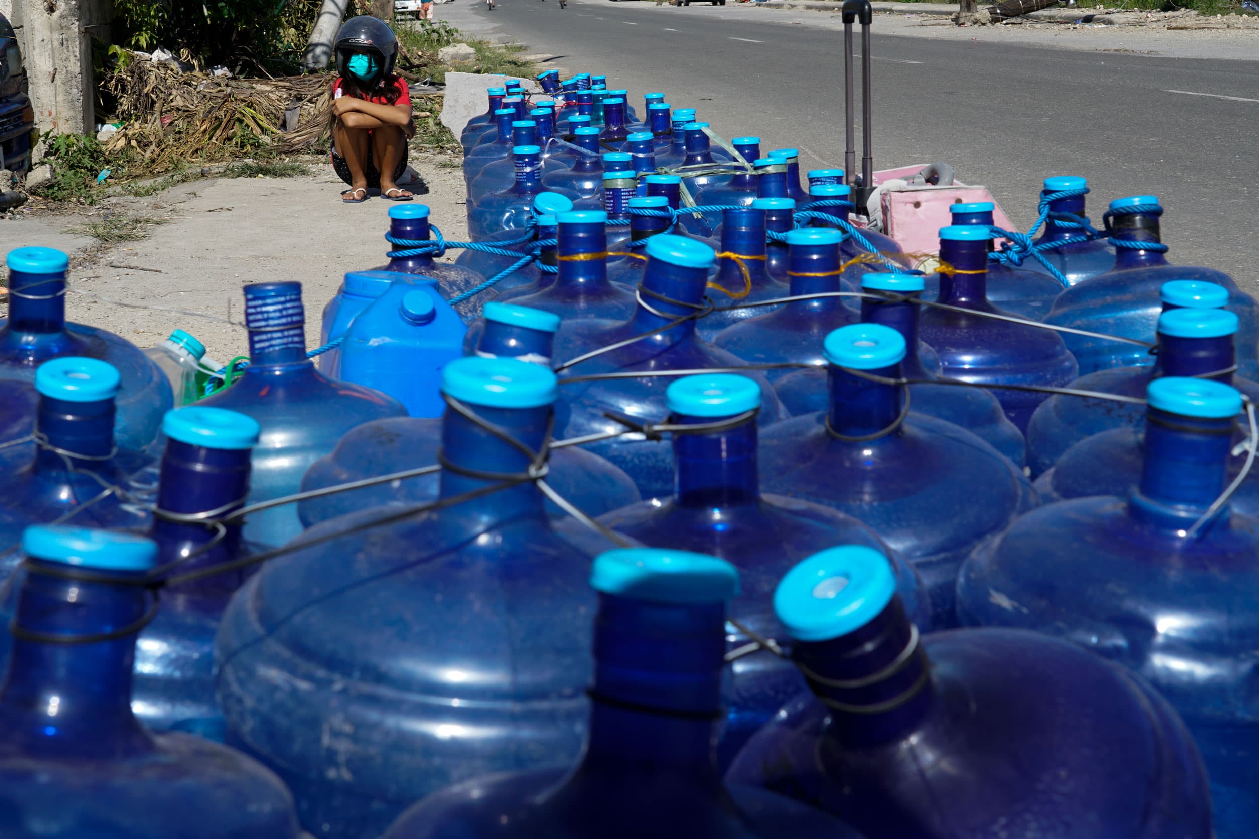 A boy sits beside water containers as residents line up for water as pipelines and electricity were damaged due to Typhoon Rai in Cebu province, central Philippines on Monday Dec. 20, 2021. 