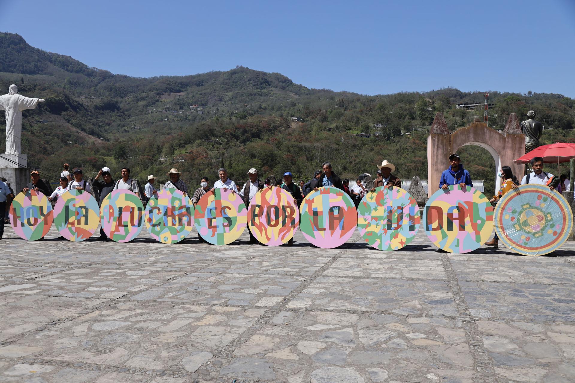 Indigenous activists in Puebla state stand in front of a colorful sign that reads 