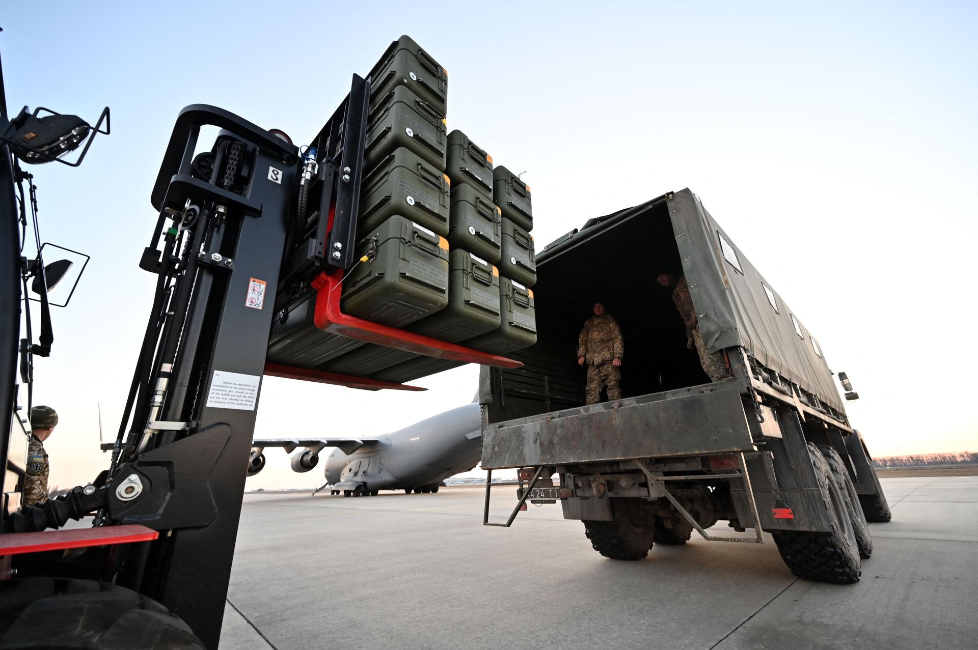 A forklift placing crates of weaponry into a military truck
