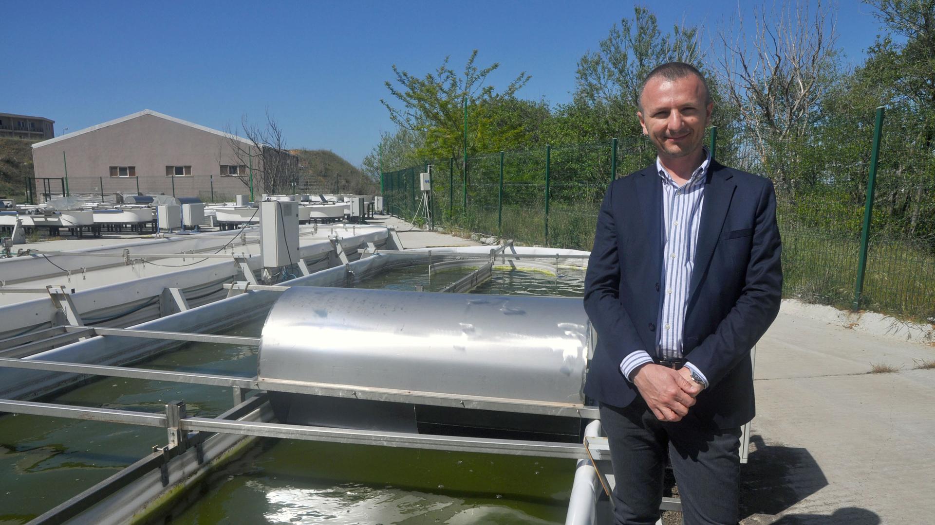 Berat Haznedaroğlu, director of the Istanbul Microalgae Biotechnologies Research and Development Center at Boğaziçi University, stands by a racetrack algae pool, a motor to one side.