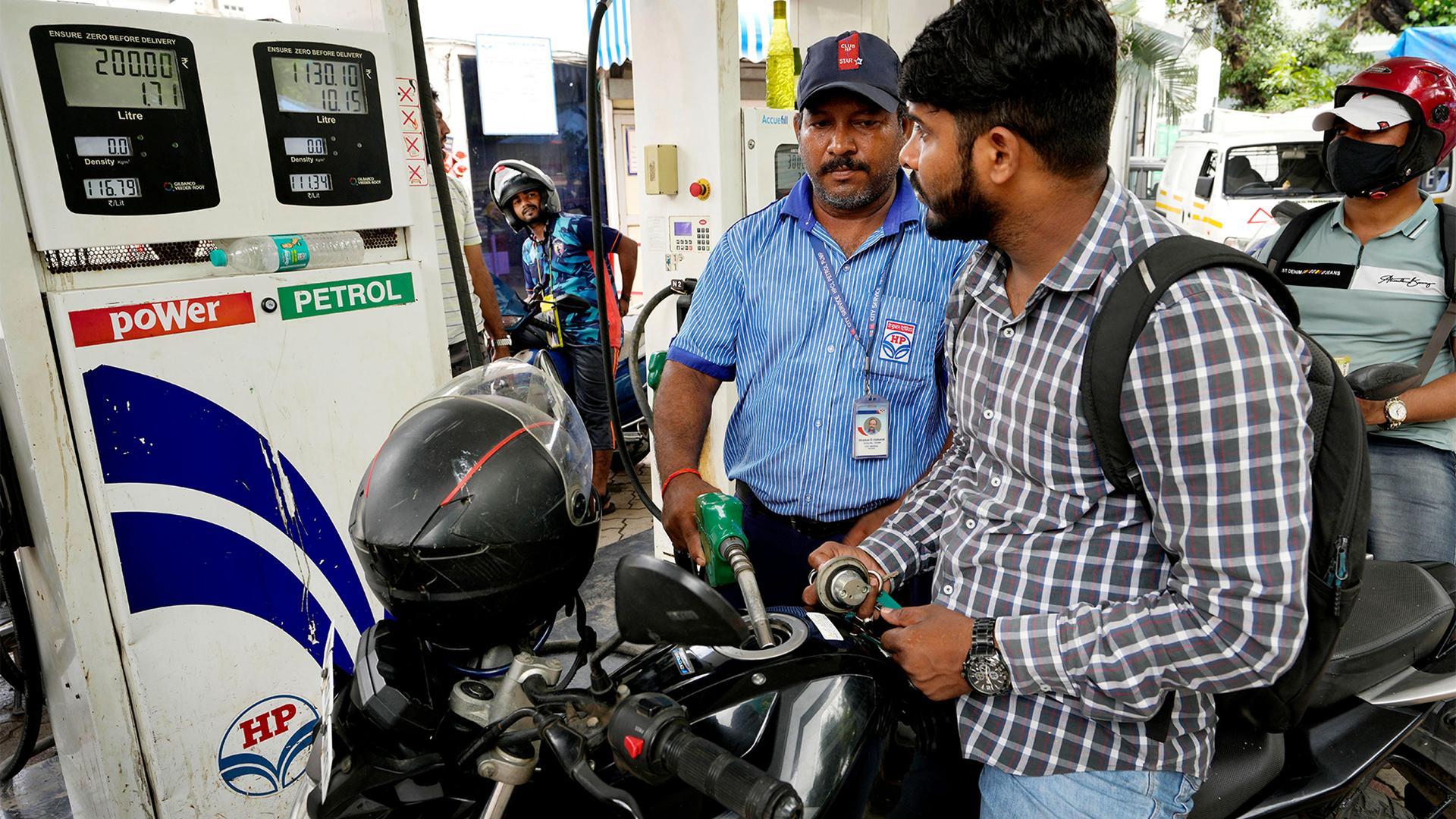 A motorcyclists watches as an employee of a fuel stationin fills petrol, in Mumbai, India