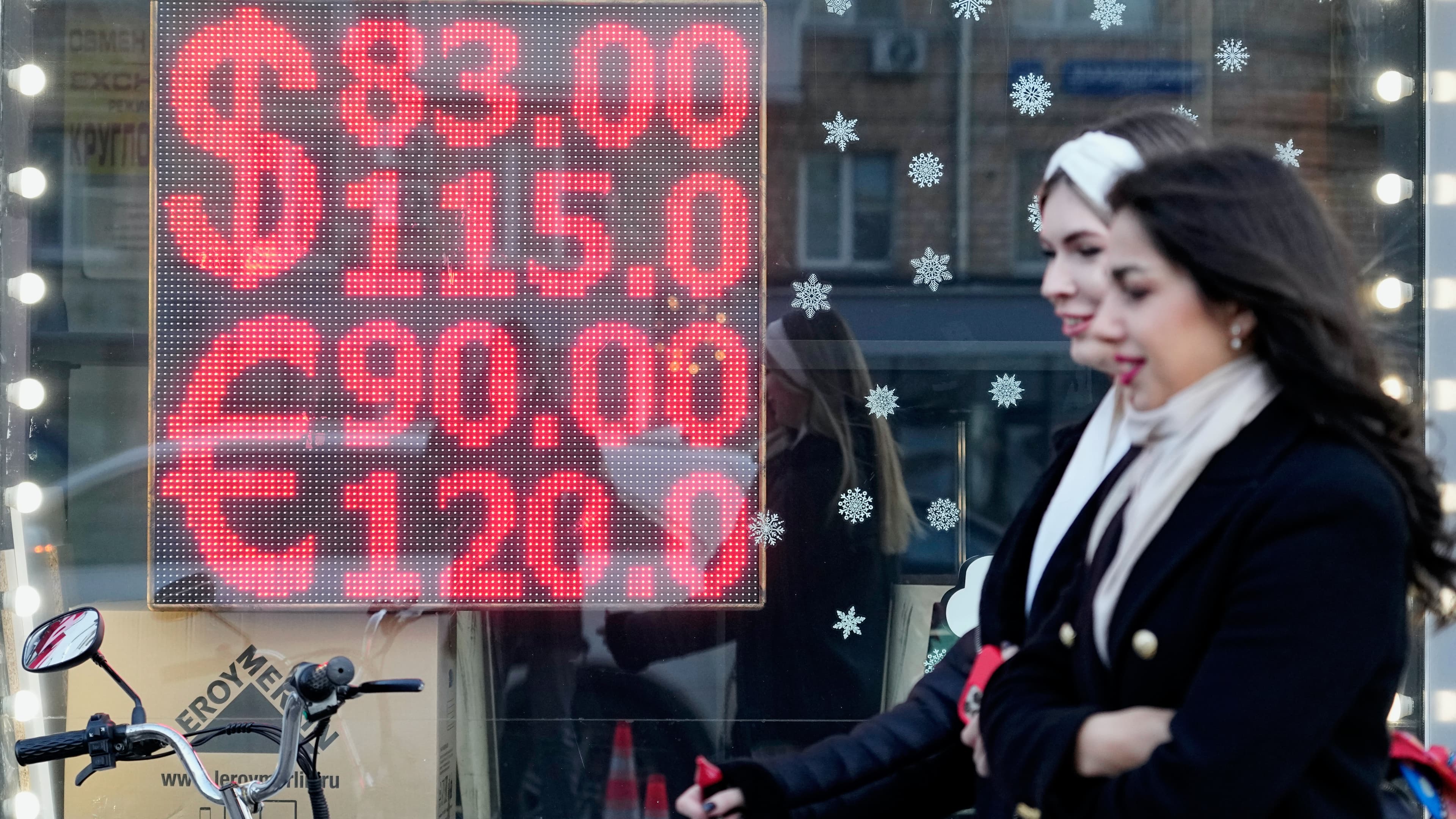 two people walk past a screen with numbers