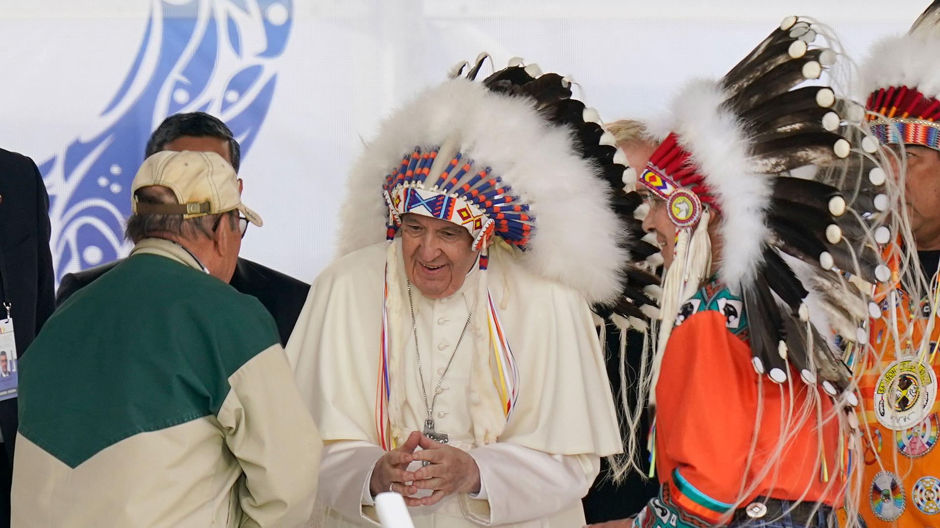 Pope Francis dons a headdress during a visit with Indigenous peoples at Maskwaci, the former Ermineskin Residential School, Monday, July 25, 2022, in Maskwacis, Alberta.