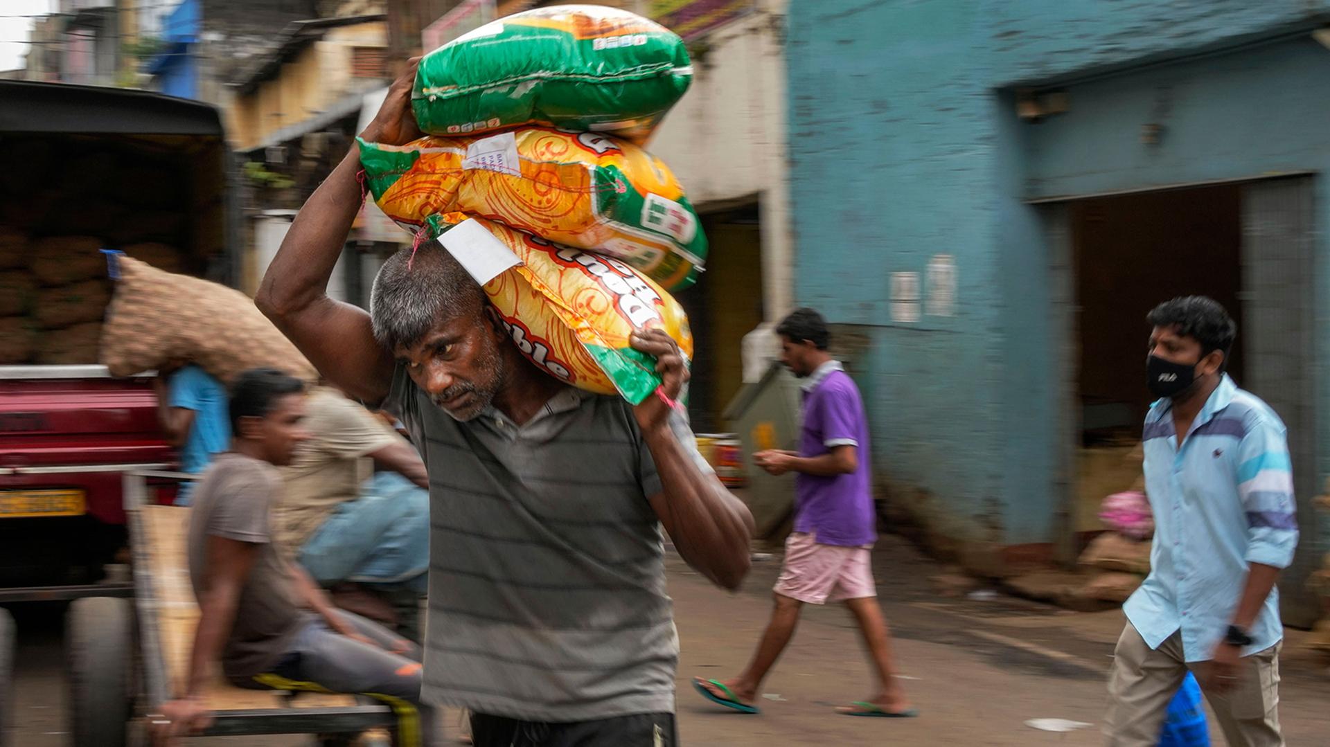 A porter carries sacks of imported food items at a market place in Colombo, Sri Lanka