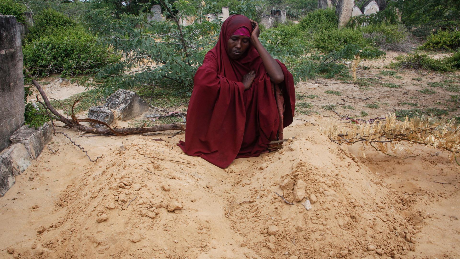 Fatuma Abdi Aliyow sits by the graves of her two sons who died of malnutrition-related diseases last week, at a camp for the displaced on the outskirts of Mogadishu, Somalia Saturday, Sept. 3, 2022. 