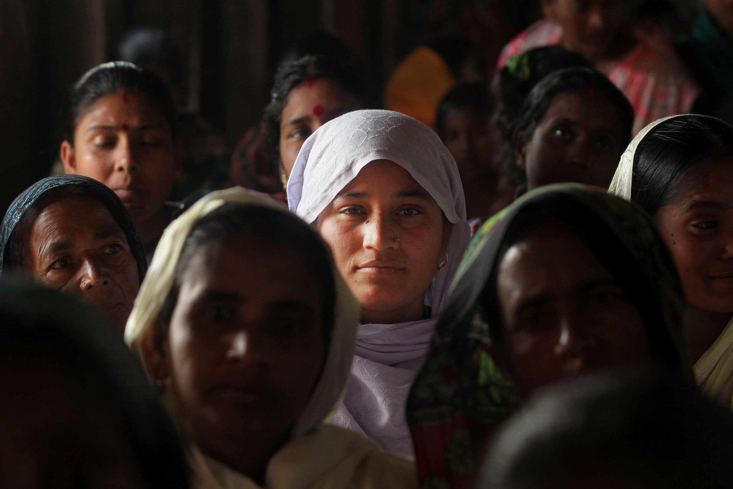 In this Monday, Feb. 10, 2014, photo, migrant women gather to attend the awareness and service camp under National Rural Health Mission at a very remote Baralakhaiti village on the sandbars of River Brahmaputra, about 43 miles north of Gauhati, India. 