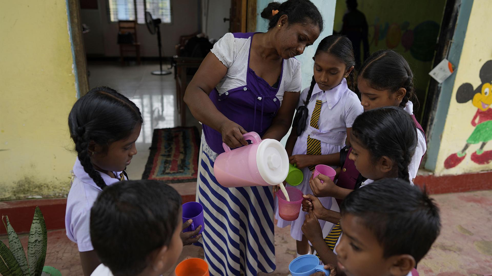 Primary students receive a cup of fresh milk at a school in Dimbulagala, north east of Colombo, Sri Lanka, Dec. 12, 2022.