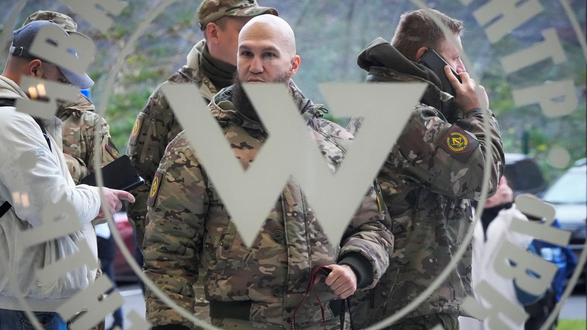 Visitors wearing military camouflage stand at the entrance of the PMC Wagner Center.