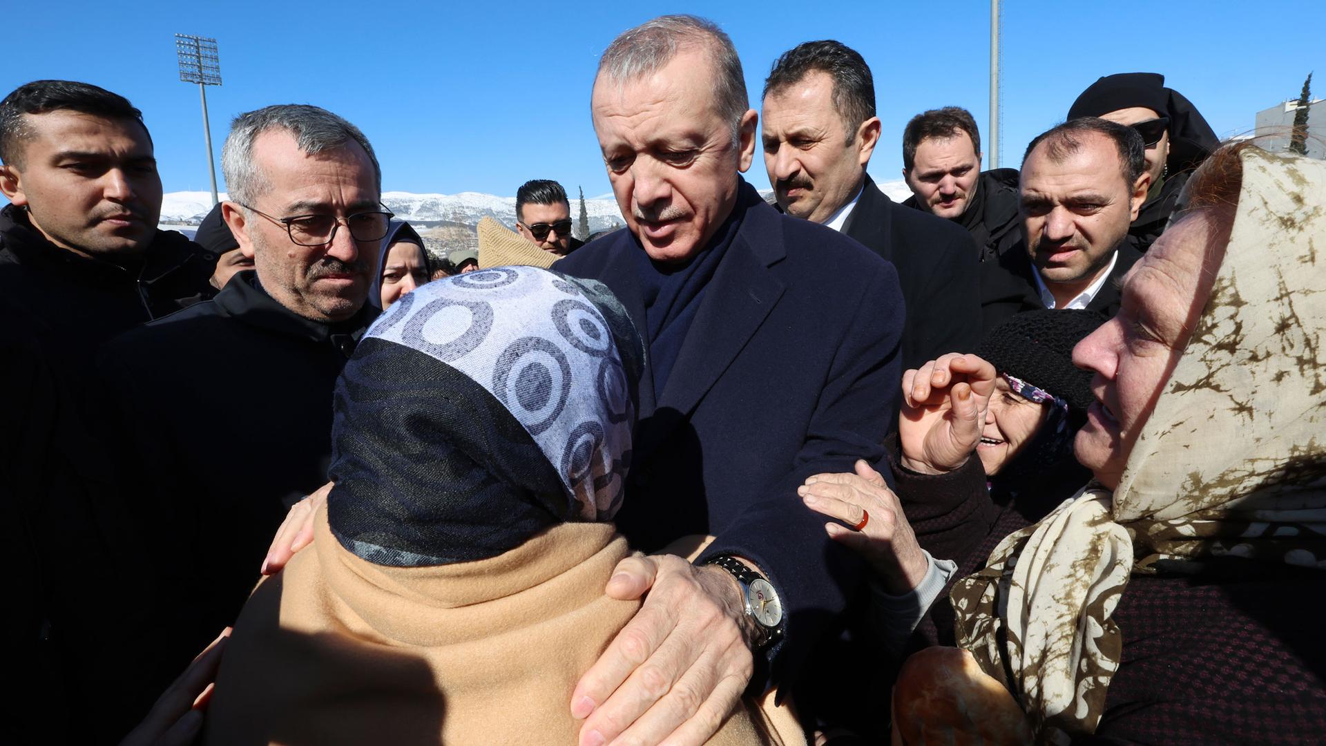 In this file photo, Turkish President Recep Tayyip Erdogan speaks with a distressed woman during a visit to the destroyed city of Kahramanmaras, Feb. 8, 2023. 