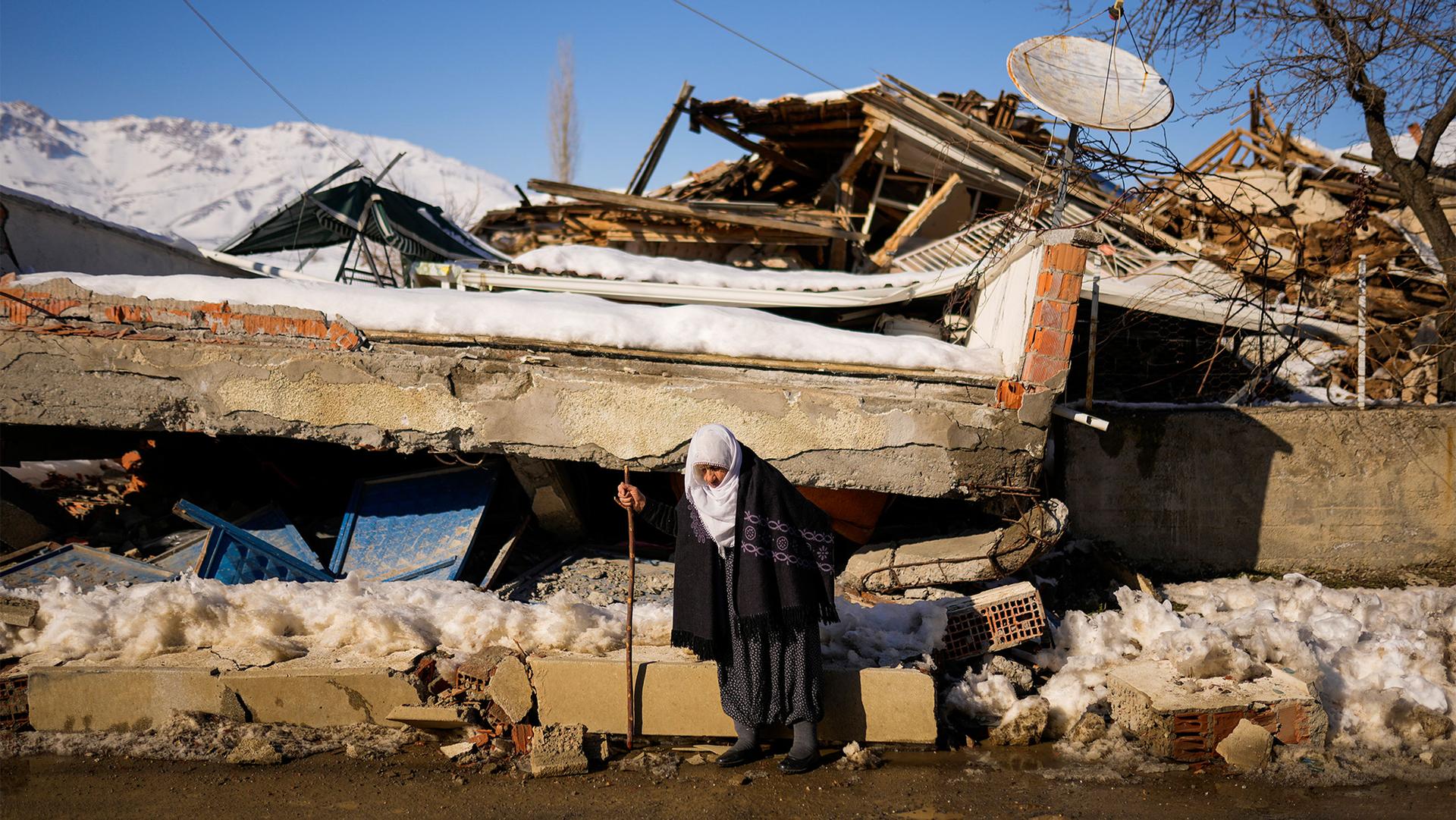 Zehra Kurukafa walks past a destroyed house in the village of Polat, Turkey, Feb. 12, 2023.