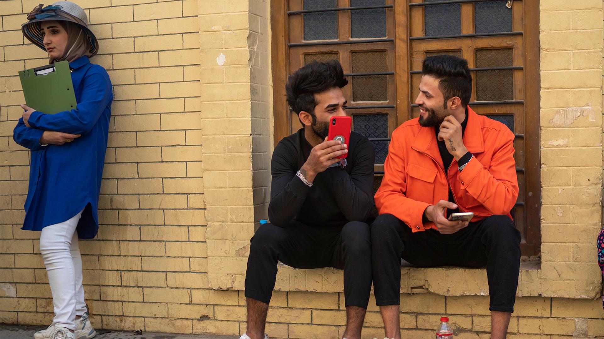 Young men chat near Al-Mutanabbi street in Baghdad, Iraq, Friday, Feb. 24, 2023.