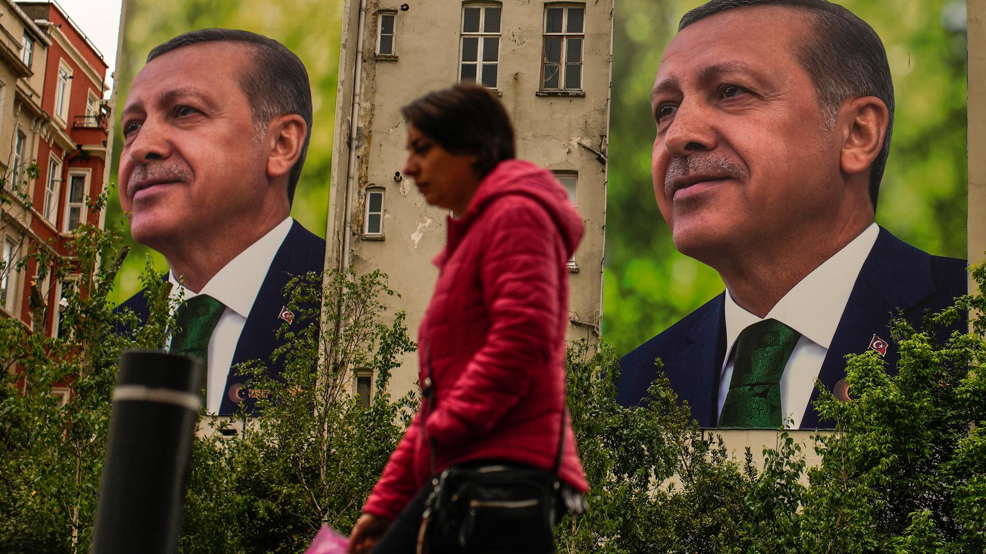 A person walks past billboards of Turkish President and People's Alliance's presidential candidate Recep Tayyip Erdogan a day after the presidential election day, in Istanbul, Turkey, Monday, May 15, 2023. 