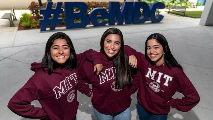three students smiling and wearing MIT sweatshirts